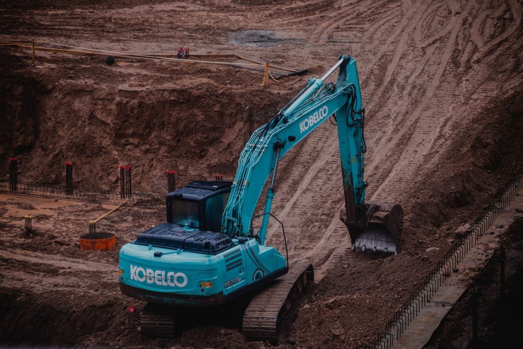 Bagger in einer ausgehobenen Baugrube mit steilen Erdböschungen
