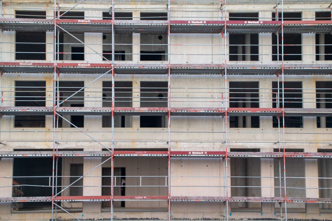 Eingerüsteter Rohbau eines mehrgeschossigen Gebäudes mit offenen Fensteröffnungen